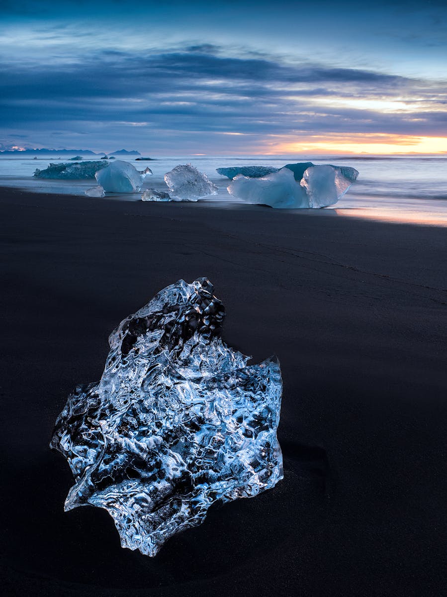 A crystal clear iceberg washed up on the black volcanic sands of the beach at Jökulsárlón, Iceland (Glacier Lagoon). This image was shot at sunrise.